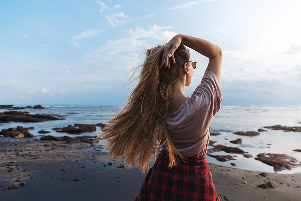 Mujer frente al mar tocándose el pelo