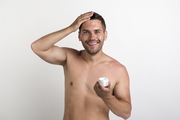 Hombre aplicándose protección solar para el pelo