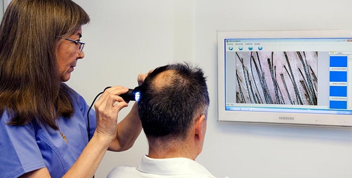 La doctora Mónica Rolando revisando el cabello a un paciente