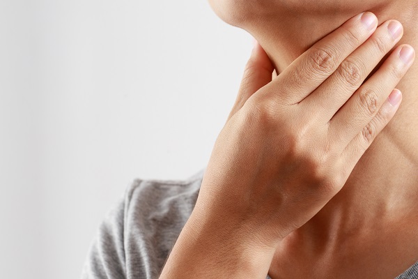 Mujer tocándose la garganta con dolor en los ganglios linfáticos