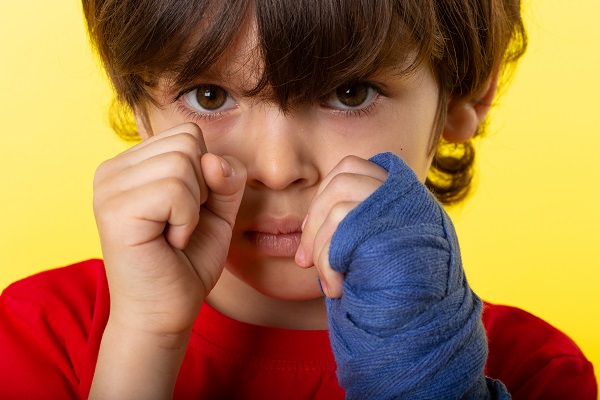 Niño con mirada triste y las manos cerradas cerca de la cara