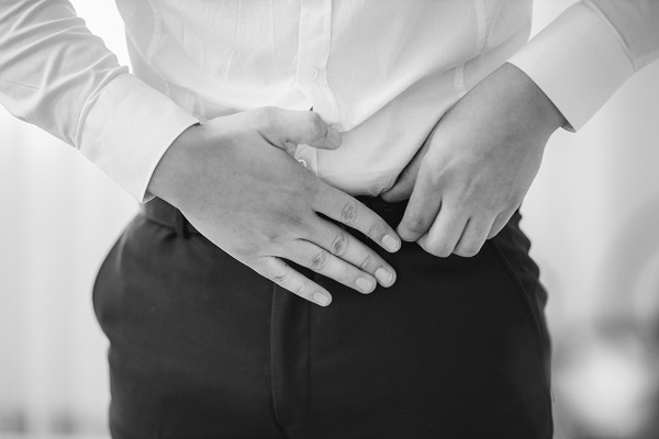 Hombre poniéndose la mano en el bajo vientre indicando un que padece HPB que es una enfermedad para la que se utiliza Dutasterida