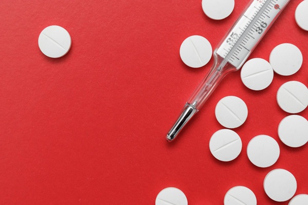 Pastillas sobre la mesa junto a termómetro representando los corticosteroides